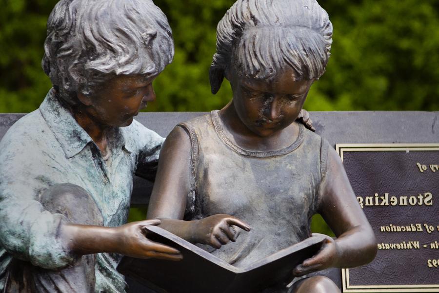 A statue of two children reading together.